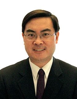 headshot of man wearing glasses and a suit